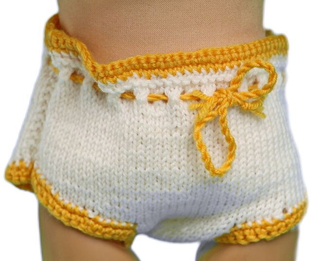 The white knitted pants, with their eye-catching crocheted yellow edges, harmonize with the dress’s detailing