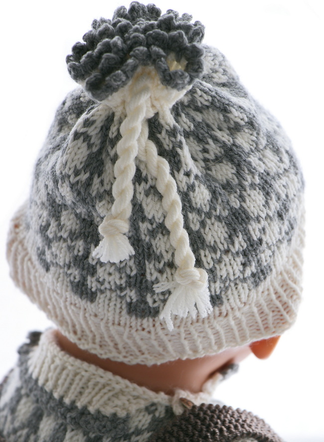 Ich habe die Mütze im gleichen Muster gestrickt wie den Pullover. Sie hat ebenfalls ein weißes Rippenmuster und graue Picots.