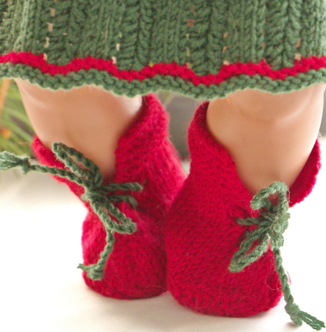 Was die Accessoires betrifft, so hat die Puppe ein Paar niedliche, rot gestrickte Schuhe.