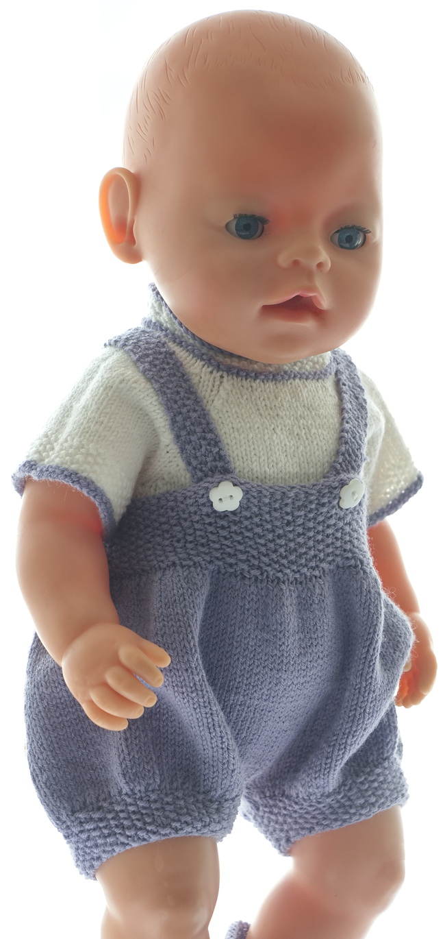 The romper is wide and knitted in lilac. Edges are knitted in moss stitch. The suspenders are knitted in moss sts and buttoned front with small white flower buttons.