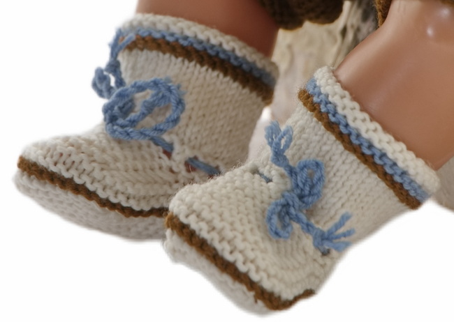 A pair of soft and inviting socks, knitted in white, to complete the outfit. Small stripes in blue and brown and a cord bound around the legs in blue make the socks perfect.