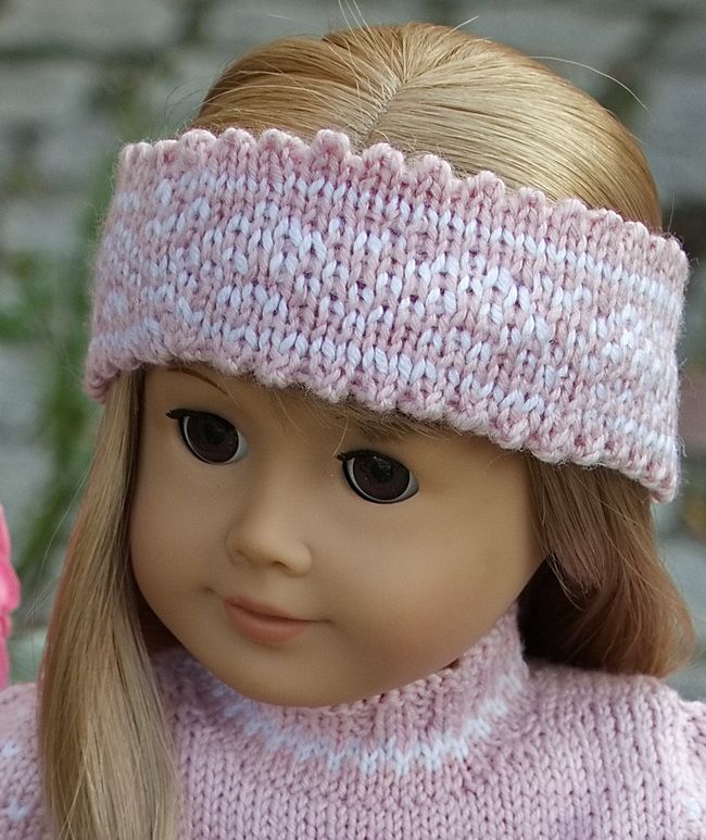 Complementing the dress is a hairband knitted in the same pink and white color scheme. The hairband follows the same pattern as the dress, ensuring a cohesive look. Your doll will be beautifully dressed with this addition.