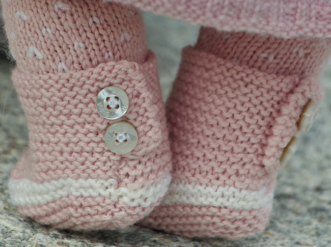 The outfit is completed with a pair of pink stocking-stitch shoes. These shoes feature a white stripe around the ankles and are buttoned along the back with nice pear buttons. Four buttons are required as accessories.