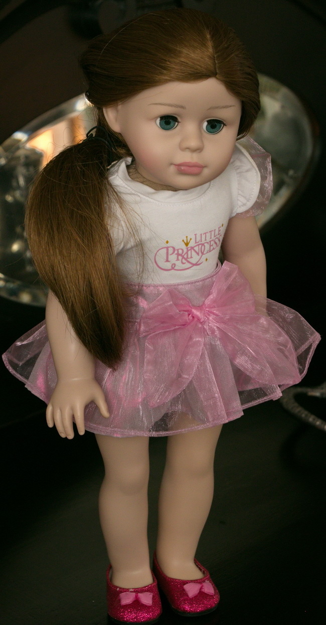 Little Princess Pop in haar originele outfit – een schattige witte trui met korte mouwen, een roze rok met een grote strik en lieve rode schoentjes met bijpassende strikken.